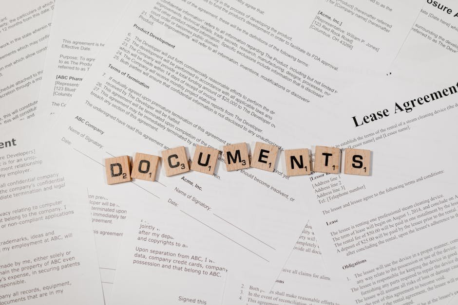 Top view of scrabble tiles spelling 'DOCUMENTS' on various contracts and agreements.